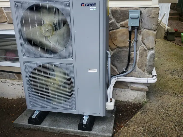 Gree inverter heat pump outdoor unit installed on a concrete pad beside a home